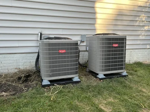 After: Two new Bryant outdoor air conditioner units on pads beside vinyl siding